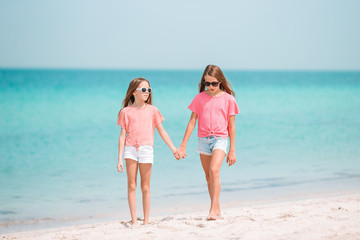 Little girls having fun at tropical beach playing together at shallow water