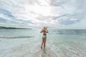 Obraz premium A girl in a hat looks at the sunset on the beach