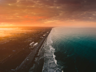 sunrise or sunset over an ocean from above looking down the coast in the blue water