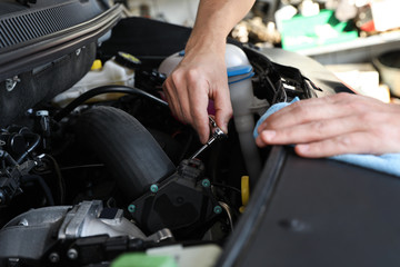 Fototapeta na wymiar Professional auto mechanic fixing modern car in service center, closeup