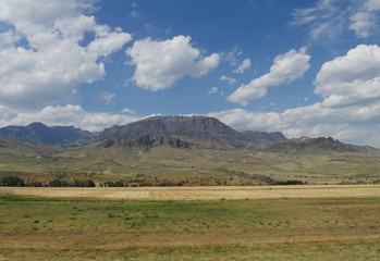 Wide shot of Wyoming landscape with mountains and rock formations in the distance.