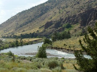 Fototapeta na wymiar Shoshone River flowing at the floot of mountains at North Fork Highway in Wyoming.