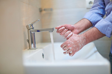 coronavirus male wahing hands in bathroom