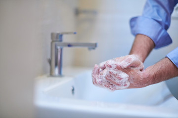 coronavirus male wahing hands in bathroom