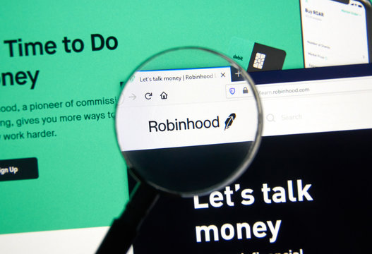 Robinhood app and logo on screen under magnifying glass