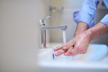 coronavirus male wahing hands in bathroom