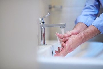 coronavirus male wahing hands in bathroom