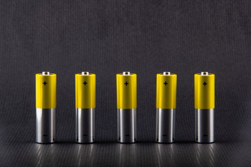 Five gray-yellow alkaline AA batteries on a gray background. The most popular size of accumulators....