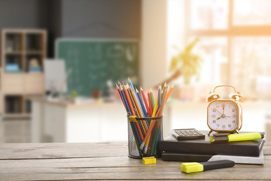 Set Of School Supplies And Clock On Table In Classroom