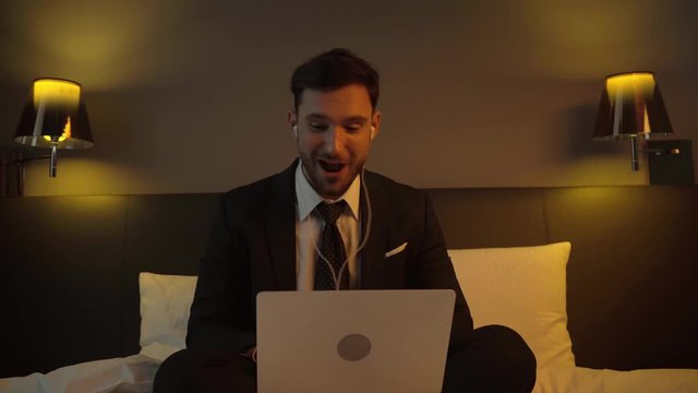 happy businessman listening music in earphones near laptop