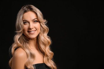 Fototapeta premium Piękna młoda kobieta z kręconymi włosami na ciemnym tle