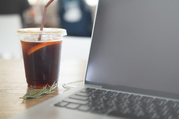 Black iced coffee on the table with laptop computer