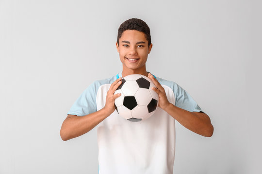 Young African-American football player on light background