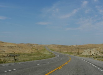 Obraz premium Paved winding road along plains and valleys of Wyoming.