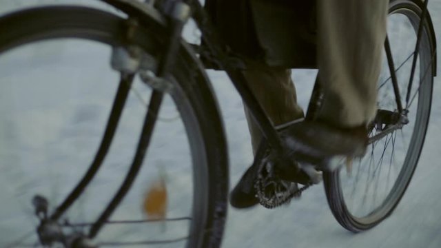 A lone person peddling a vintage bicycle on snow covered road carrying a leather attache