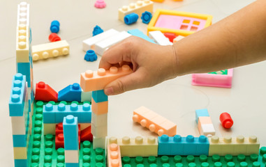 Close up, A child right hand playing with colorful plastic bricks.