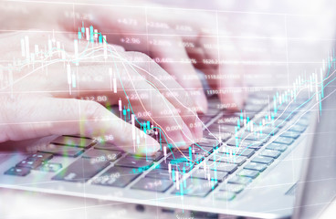 working on a computer in the business office with concept graph of financial data curve chart