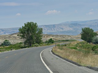 Montana landscape with a road winding around rolling hills.