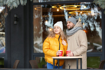 Happy young couple drinking hot cocoa in cafe outdoors