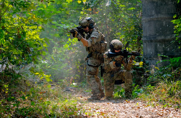 Two soldiers with the fighting uniform sit on the ground and discuss together for the battle in...