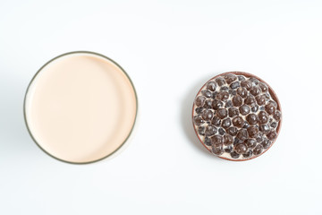 A glass cup of pearl milk tea (also called bubble tea) and a plate of tapioca ball on white background. Pearl milk tea is the most representative drink in Taiwan. Taiwan food . With copy space.