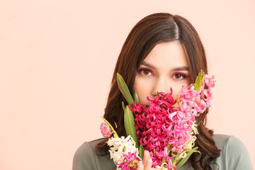 Beautiful young woman with hyacinth flowers on color background