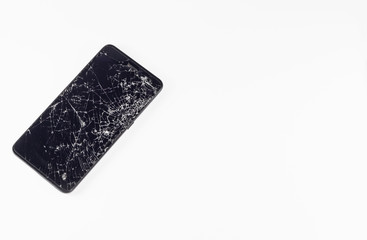 Mobile smartphone with broken touch screen isolated on white background. LCD with many cracks and little pieces of glass. Top view, copy negative space, phone repair concept.