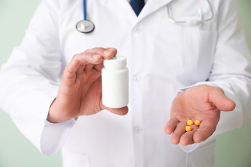 Senior doctor with pills on color background, closeup
