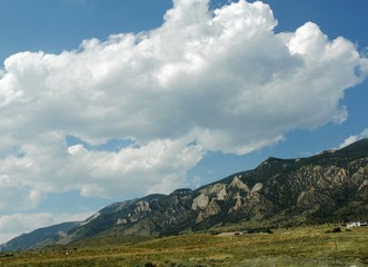 Stunning mountainside view with thick cotton clouds in the skies along North Fork Highway in Wyoming.
