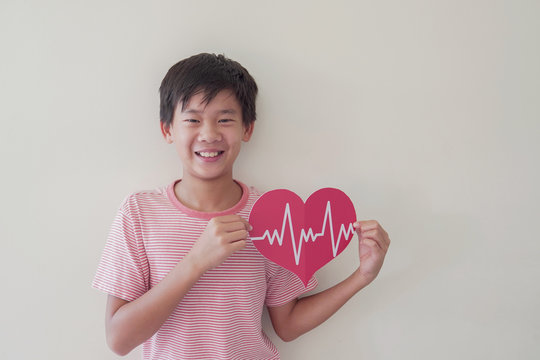 Mixed race child holding big red heart with cardiogram,  children health care, life insurance business concept, world heart day, world health day - Powered by Adobe