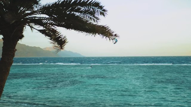 Kite surfing in beautiful clear water in Dahab Egypt. Exploring the blue water with mountains in the background and people windsurfing and kite surfing, slow motion, 4k
