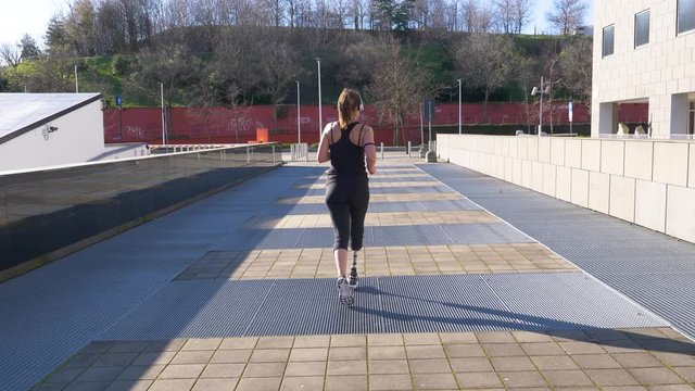 Slow motion shot of jogging woman with leg prosthesis in the city