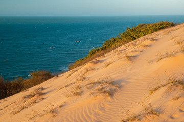 Top view of the famous dune of Ponta Grossa Beach, Icapui, Ceara, Brazil on September 5, 2016, highlighting the texture of the sand and natural vegetation with the sunset in the background