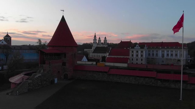 Aerial of Kaunas castle in the early morning with pink sky and a light breeze blowing the Coat of arms of Lithuania