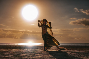 silhouette of young stylish tribal woman in turban outdoors at sunset