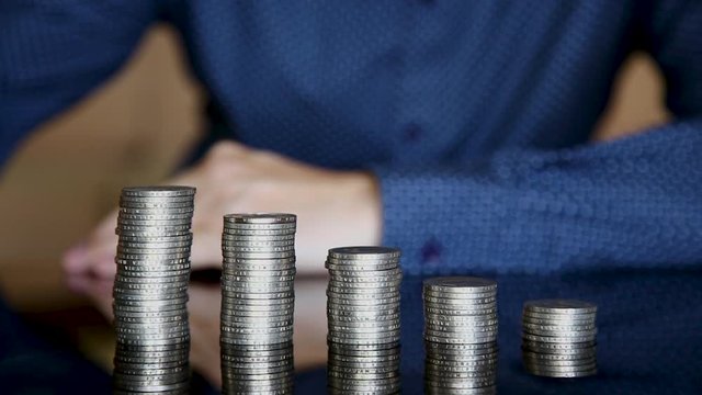 Close-up hands make up stacks of coins.