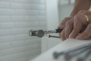 The mechanic assembled the furniture in the house according to the manual, along with the mechanic equipment. By hammering the nails Measuring with a tape measure Screwing the screw Drilling holes.