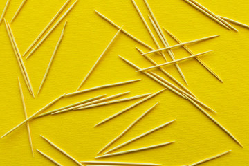 Lots of wooden toothpicks on a yellow background. The concept of order and chaos.