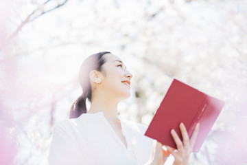 満開の桜の中で読書をする女性