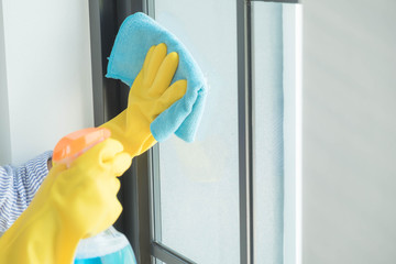 The cleaning staff uses a cloth and dust brush on the window surface with blinds and uses cleaning agents to kill germs and viruses.