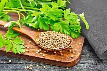 Coriander seeds in wooden spoon on black board
