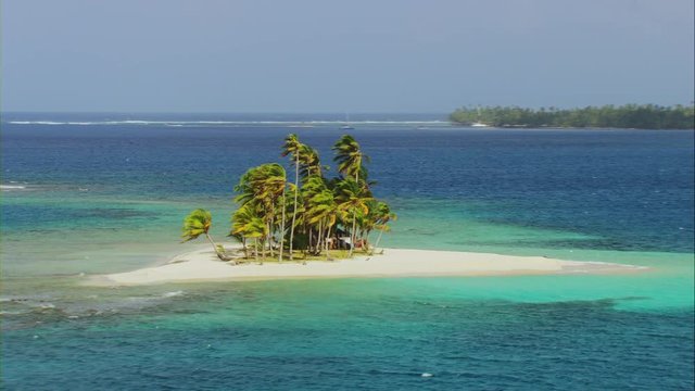 Panoramic aerial view and approach to paradise island with white sand, crystal clear waters and indigenous house, filmed in 4K, daytime with Cineflex stabilization camera systems