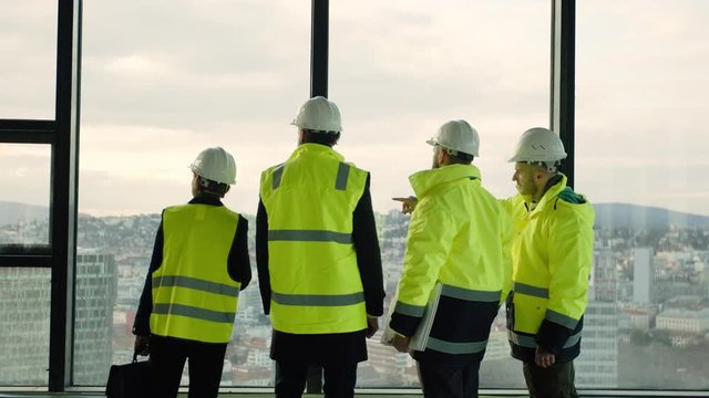 Group of engineers walking on construction site, talking.