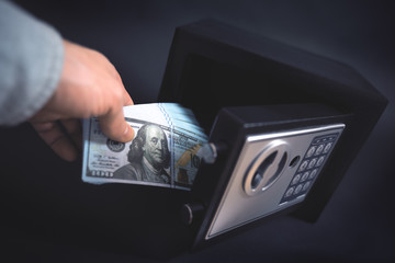 Cash Money Safe Deposit. Symbol of money safety. The man puts a wad of dollars in small Residential...