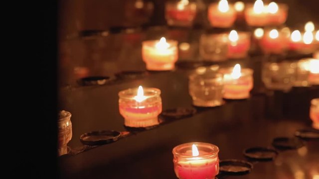 the camera moves around candles burning in the temple