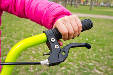 Children's hand on the handlebars of a bicycle. Background for entertainment and sports.