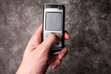 Close up of male hand press on button of an obsolete cellphone.