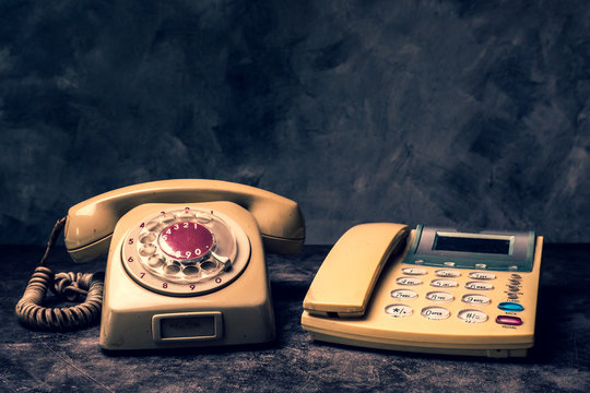 An old telephone with rotary dial and a landline on a grunge background.