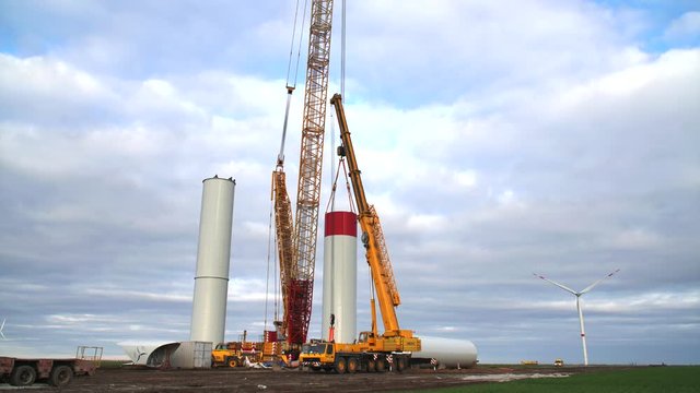 Building process of wind energy power tower mill, under construction. Time-lapse. Assembling rotor, tower, column, pillar. Green, clean, renewable energy. 