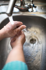 Obraz premium Wash hands with soap. Female hands under a kitchen faucet